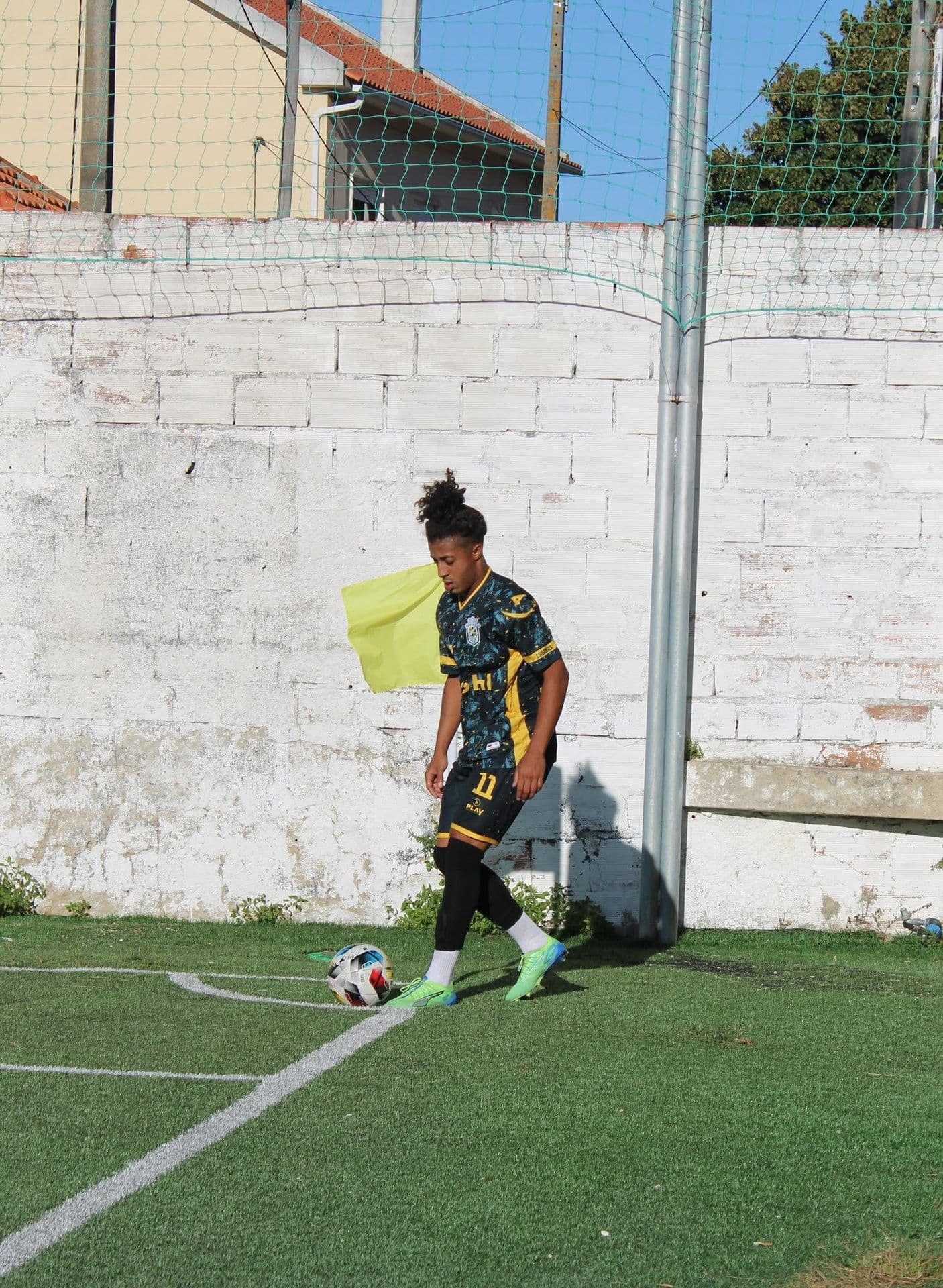 Jogador de futebol junto à linha com equipamento personalizado