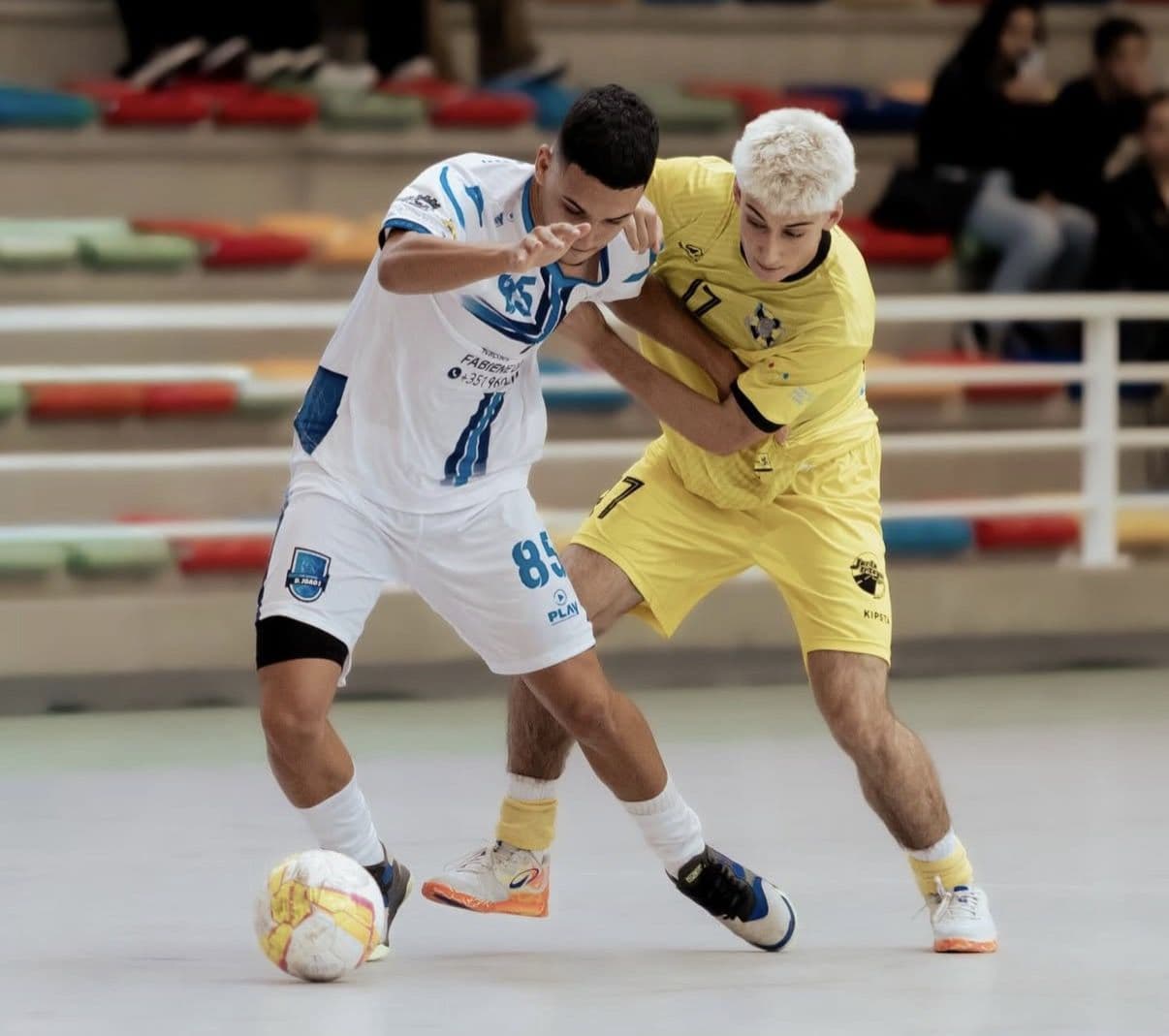 Disputa de bola num jogo de futsal com equipamentos personalizados